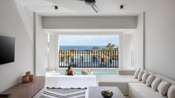 Ein modernes Wohnzimmer mit großem Fenster und Blick auf Pool und Meer.