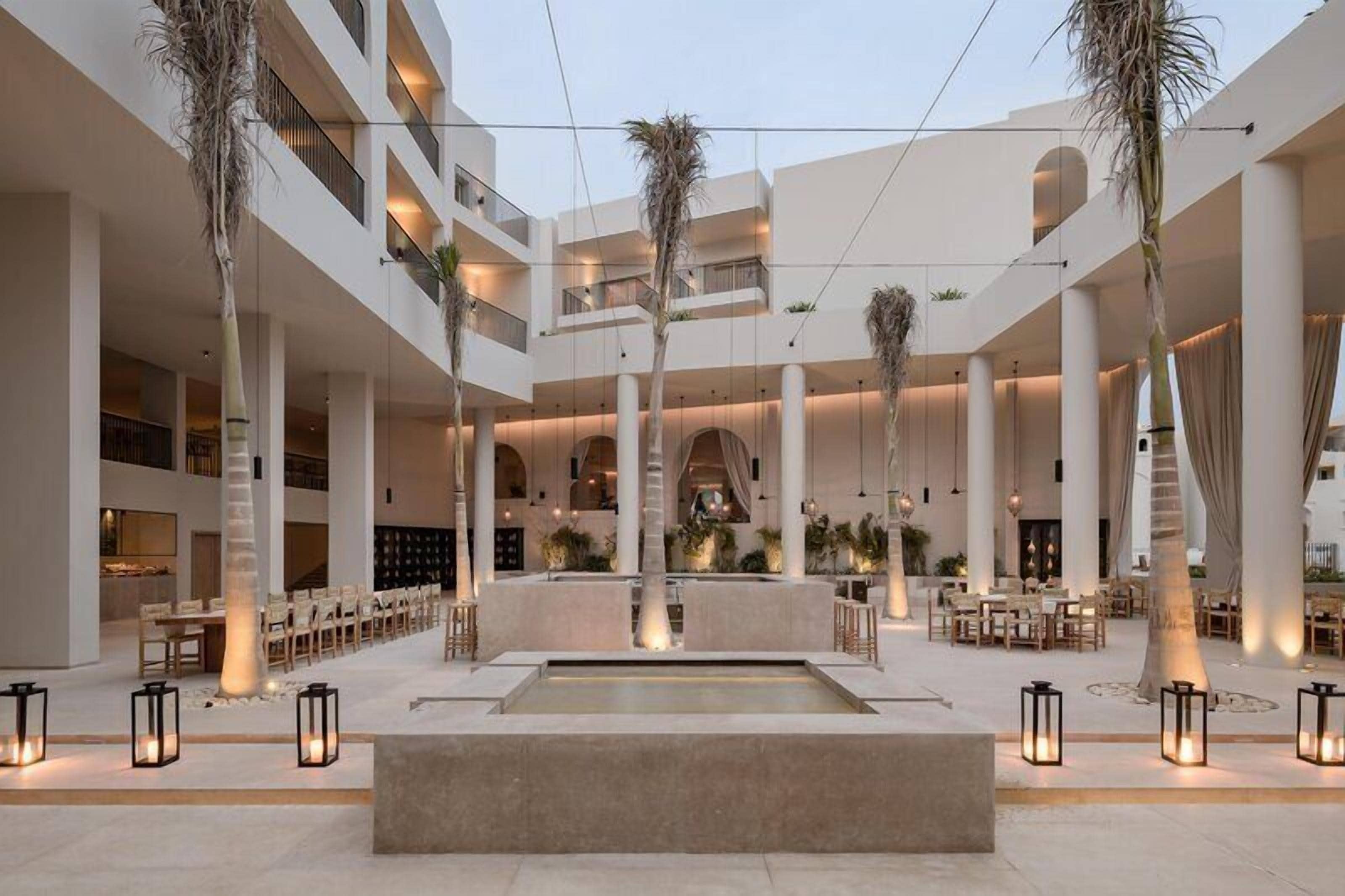 A multi-level hotel atrium with a central water feature, multiple seating areas, and a modern architectural design.