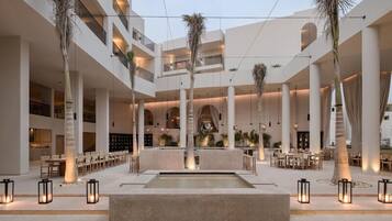 A multi-level hotel atrium with a central water feature, multiple seating areas, and a modern architectural design.