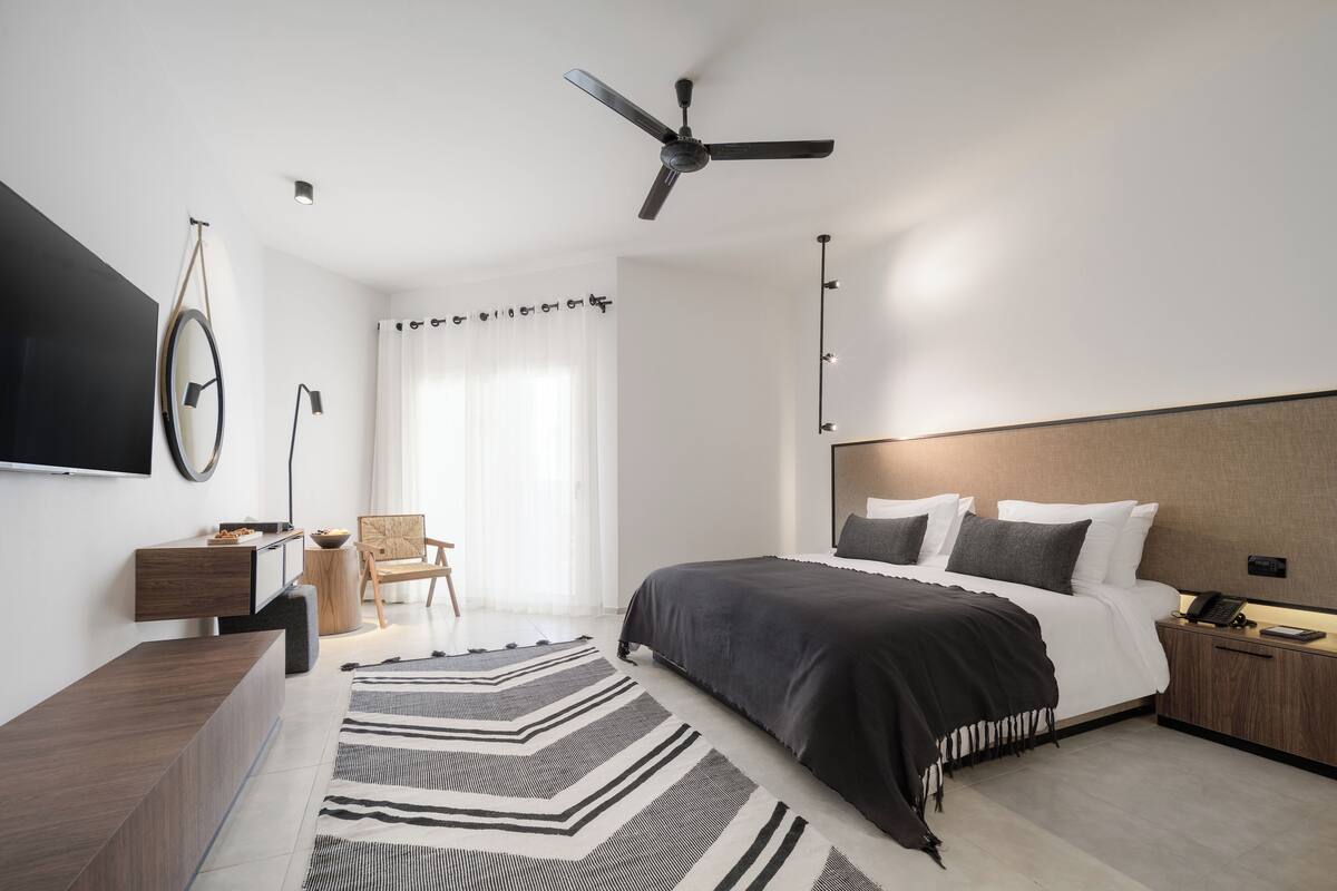 A modern bedroom with a bed, bedside table, and a ceiling fan.