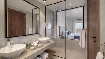 Een moderne badkamer met een grote spiegel, een wastafel op voet, een douche met glazen wanden en een houten wastafelmeubel.