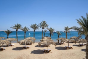 A beach with palm trees, sun loungers, and thatched umbrellas. - Serry Beach Resort (Hurghada)