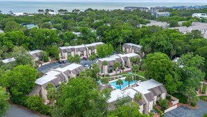 A resort with multiple buildings, a central swimming pool, and a view of the ocean. - Beachy & Beautiful Renovated Villa Just Steps from (Hilton Head Island)