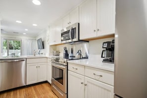 A modern kitchen with white cabinetry, stainless steel appliances, and a window providing natural light.