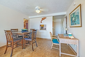A dining area with a wooden table and chairs, a ceiling fan, and a wall-mounted picture frame.