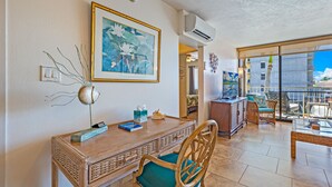 A room with a dining table, chairs, a framed painting, and a view of the outside. - Ocean View Sleeps 8 Across from Beach 3 bedroom 3 bathroom Full AC Kihei Condo  (Kihei)