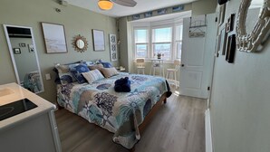 Un dormitorio con cama, ventilador de techo, ventana con vistas y puerta.