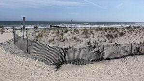 Una playa arenosa con una valla de madera y un poste de señalización.
