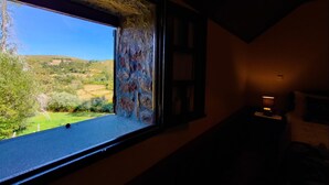 A room with a large window overlooking a green landscape.