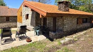 Un edificio in pietra con tetto in tegole, area esterna con tavoli e sedie.