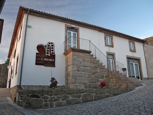 A building with a sign for 'Museu de Cinema de Melgaço' and a stone staircase leading to the entrance.