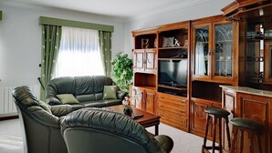 Una sala de estar con un sofá de cuero, armarios de madera y un televisor.