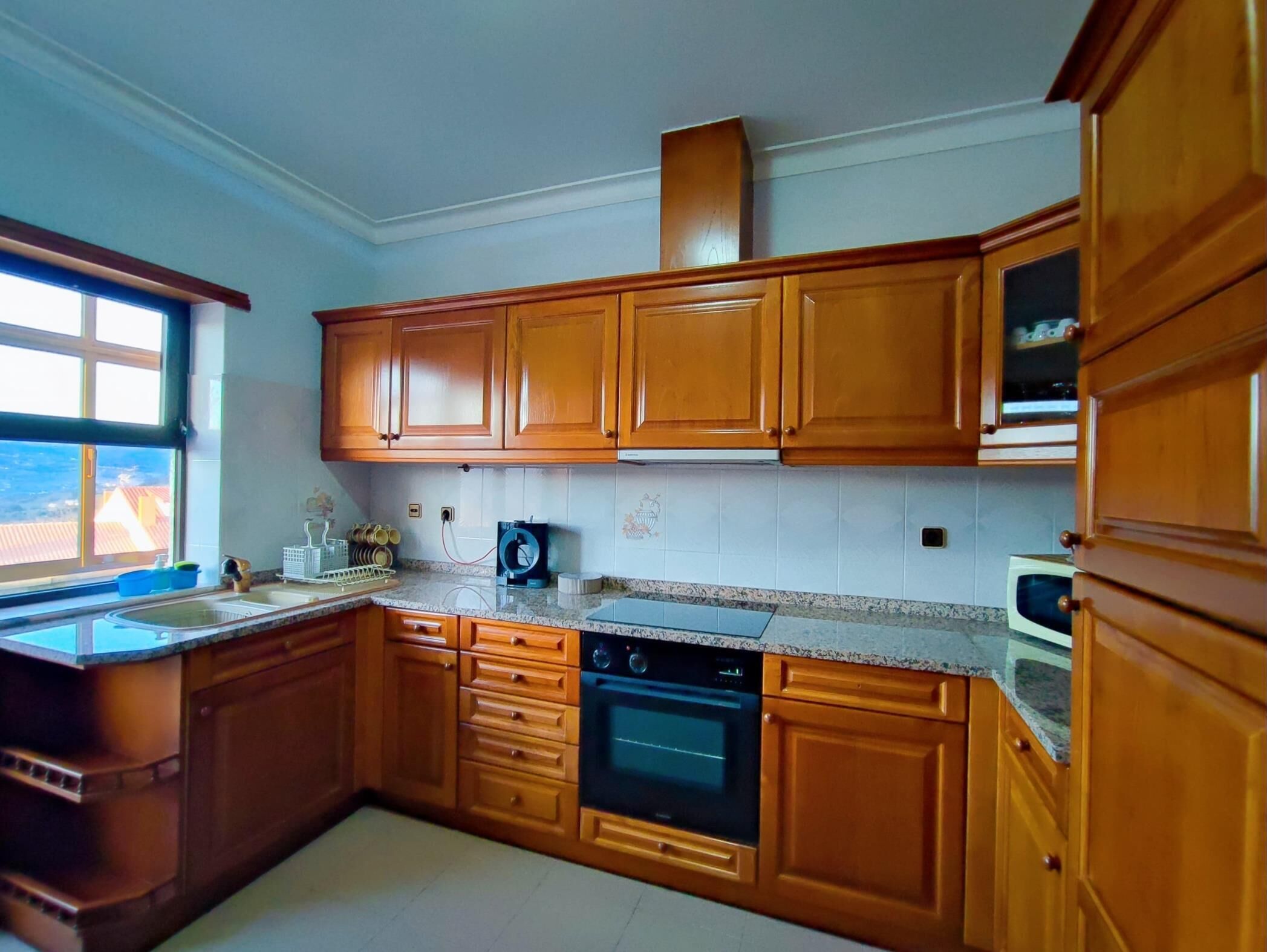 A kitchen with wooden cabinets, a built-in oven, and a microwave.