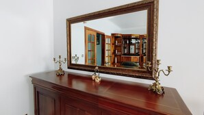 Un espejo grande y ornamentado sobre un tocador de madera con dos candelabros.