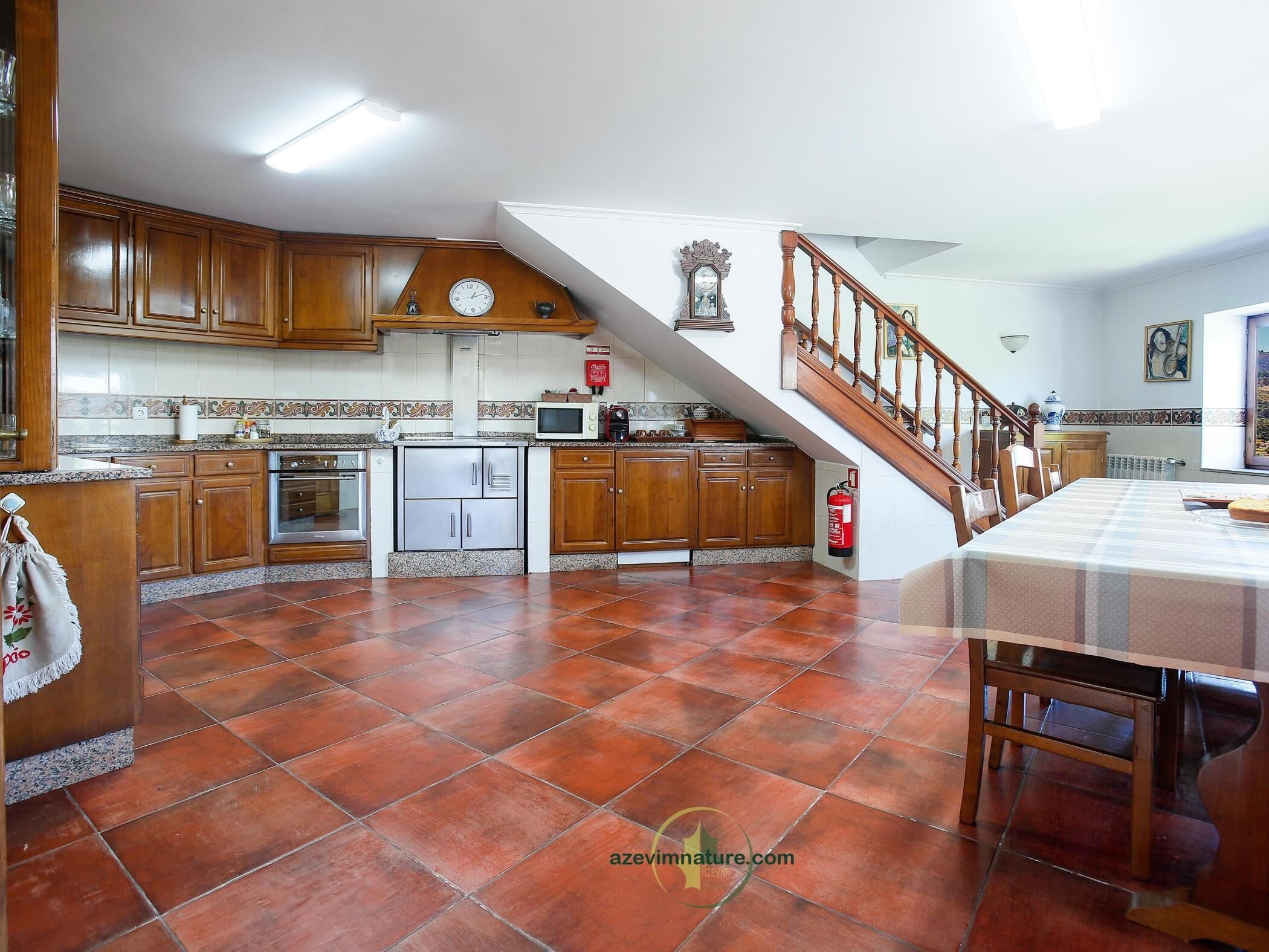 A spacious kitchen with wooden cabinets, a stainless steel oven, and a tiled floor.