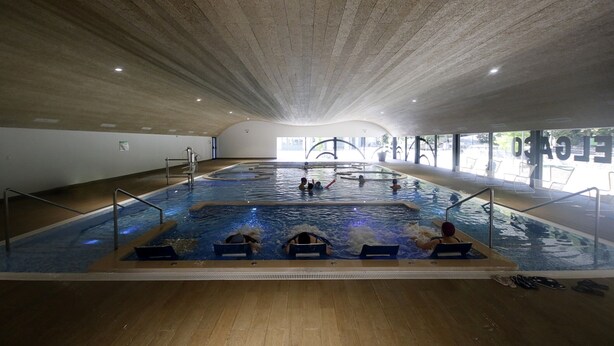 Una piscina interior con varias pistas, suelo de madera y techo alto.