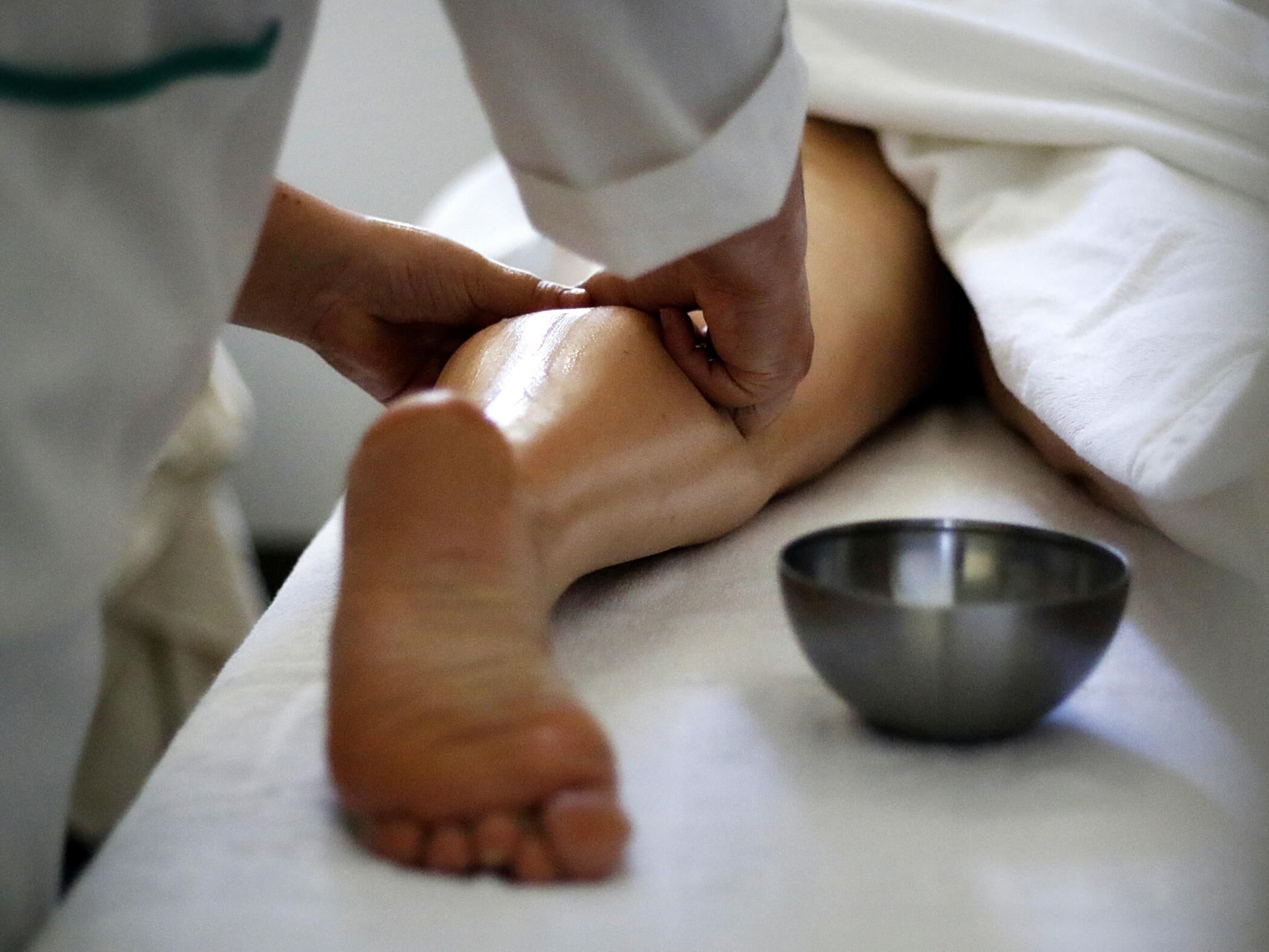 A foot massage with a metal bowl on a table.