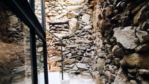 Un étroit couloir en pierre, avec une porte en verre et une rambarde en métal.