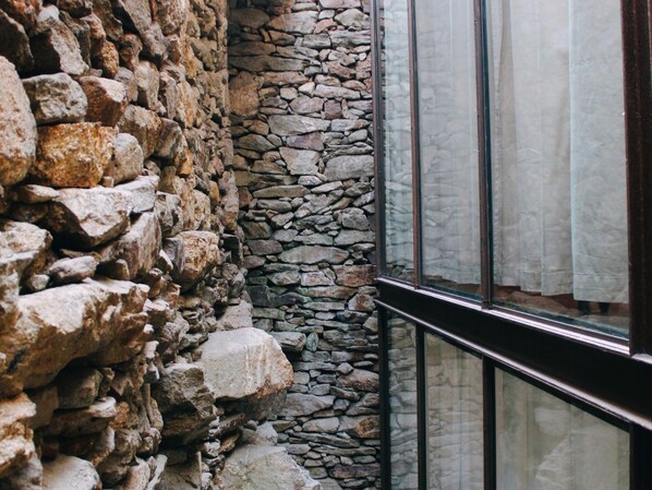 A stone wall adjacent to a glass window with a metal frame.