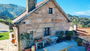 Una casa de piedra con tejado de tejas, una ventana pequeña y un banco en el exterior.