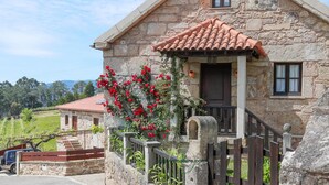 Una casa de piedra con techo de tejas, un porche de madera y una ventana pequeña.