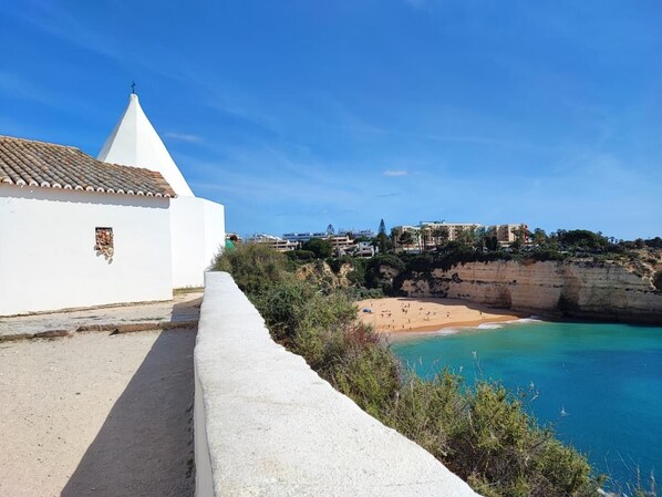 A coastal view with a white building, a beach, and cliffs.
