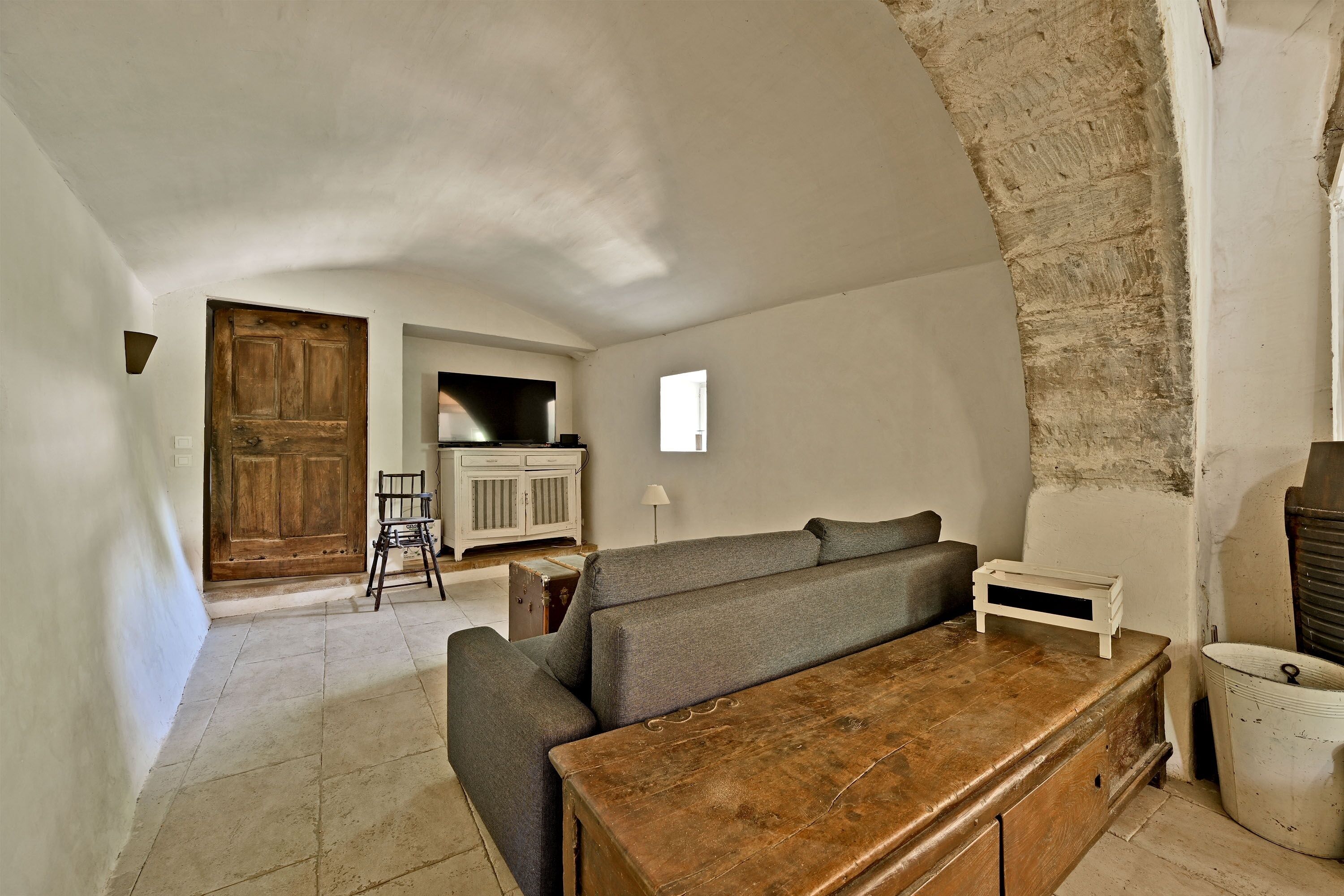 A rustic room with a wooden bench, a sofa, a cabinet, and a door.