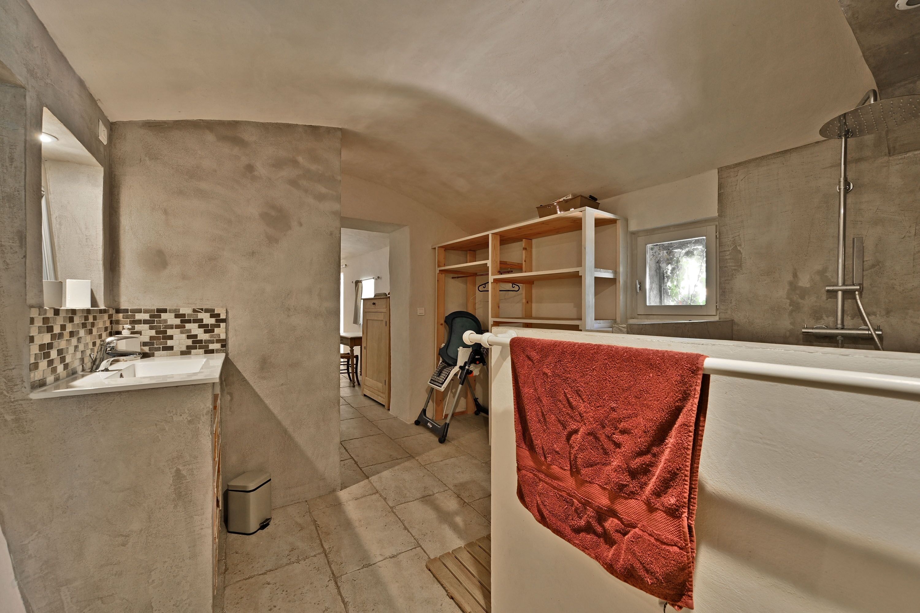 A modern bathroom with a large shower, a sink, and a towel rack.