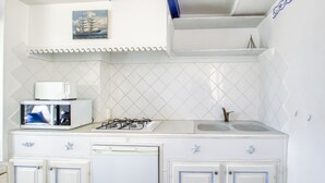 A kitchen with a microwave, stove, and sink. There is a decorative painting above the stove and a blue decorative trim on the ceiling.