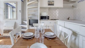 A dining area with a wooden table set for four, white chairs, and a white cabinet with a microwave.