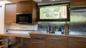 Een kleine keuken met houten kastjes, een roestvrijstalen koelkast en een magnetron.