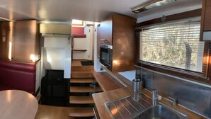 Een compact interieur met een zithoek, een kitchenette en een raam met uitzicht.