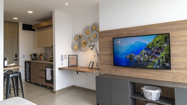 A modern kitchen with a wooden countertop, a built-in oven, and a wall-mounted TV displaying a scenic landscape. - LUXURY STUDIO (Cali)