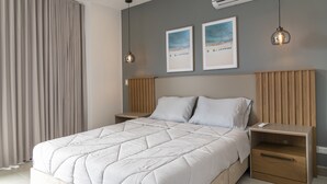 A modern bedroom with a large bed, wooden headboard, two bedside tables, and a nightstand with a drawer. - LUXURY STUDIO (Cali)