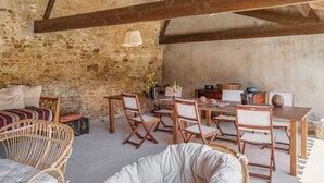 A rustic room with exposed wooden beams, stone walls, and a dining area with wooden furniture. - Maison Familiale en Centre Historique (Talmont-Saint-Hilaire)