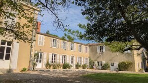A two-story building with a symmetrical facade, large windows, and a central entrance. - Maison Familiale en Centre Historique (Talmont-Saint-Hilaire)