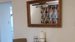 A room with a round table, two chairs, a mirror, and a patterned rug.