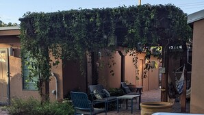 A backyard with a hot tub, outdoor seating, and a pergola covered with vines.