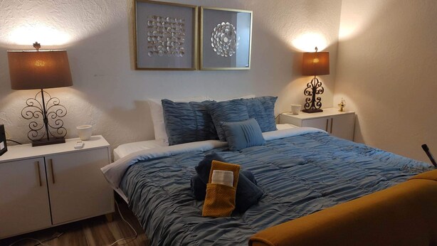 A neatly arranged bedroom with a bed, two bedside tables, and two wall-mounted lamps.
