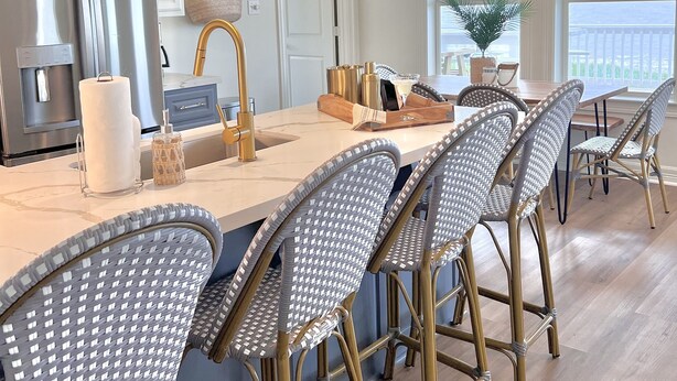 A modern kitchen with a large island, wicker chairs, and pendant lights. - Crystal Cove Cottage - BEACHFRONT Luxury Getaway - Fully Fenced & Pet Friendly (Bolivar Peninsula)