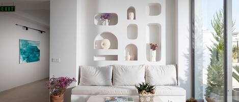 A modern, minimalist lobby with a white sofa, a coffee table, and decorative vases.