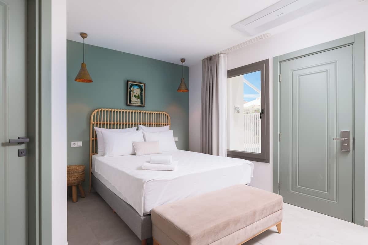 Een moderne slaapkamer met een bed, nachtkastje en een bankje.