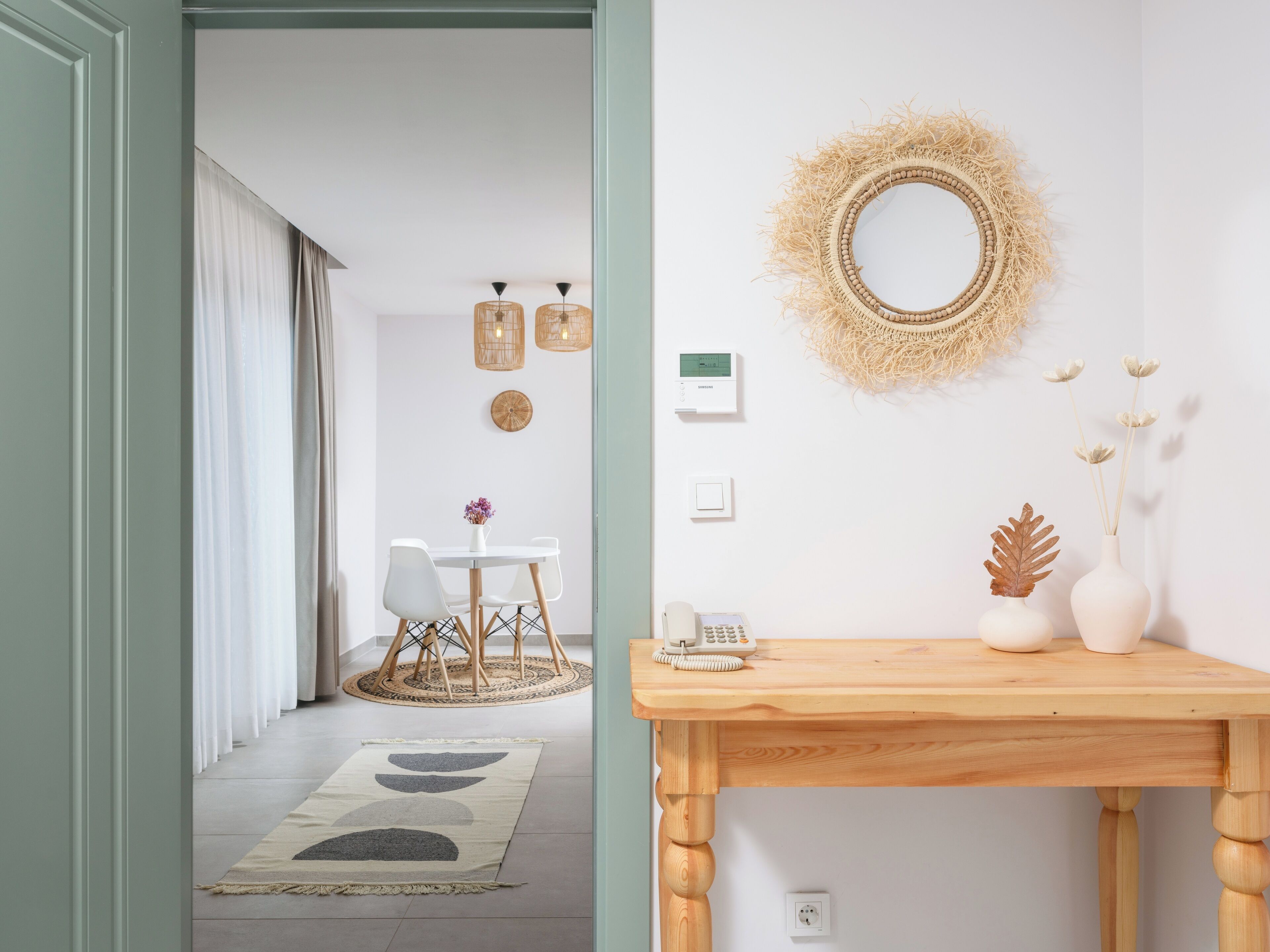 Un interior moderno con una zona de comedor, una consola de madera y un espejo decorativo.
