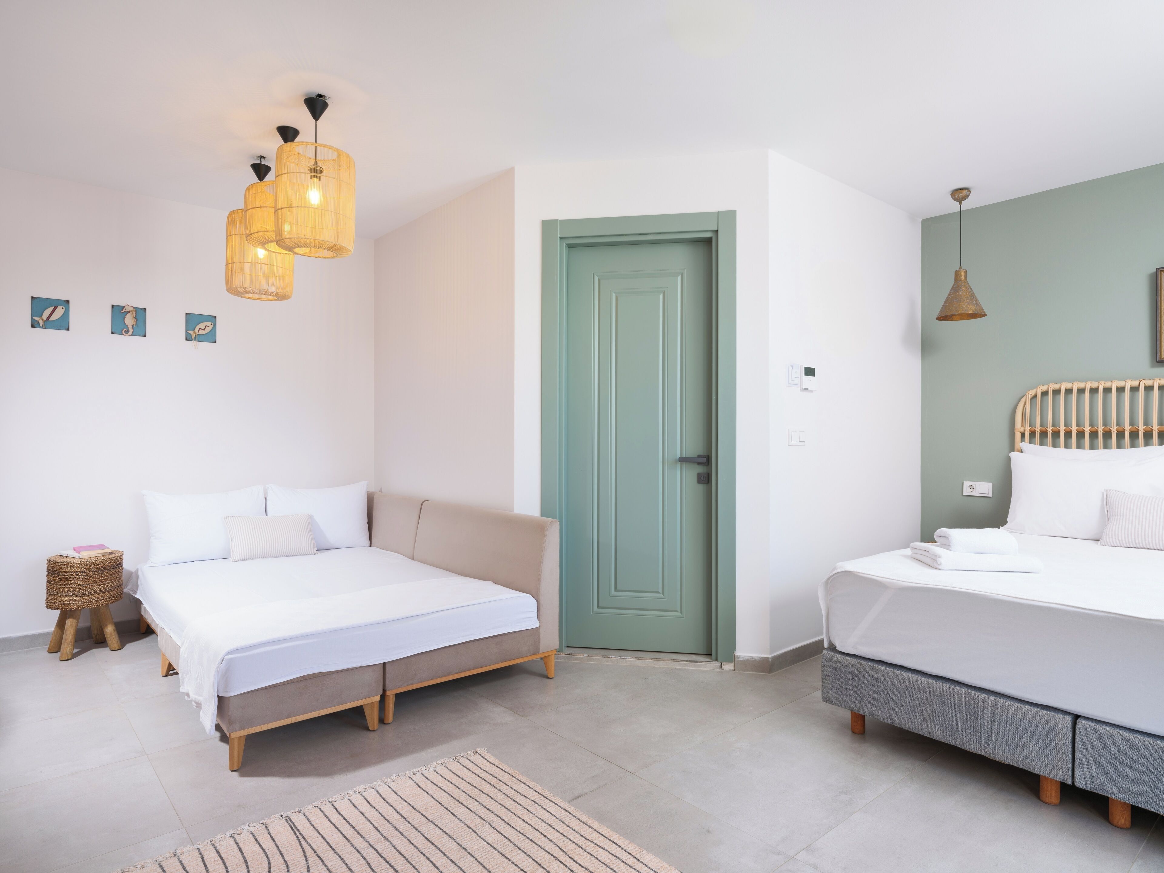 A bedroom with two beds, a green door, and a hanging light fixture.