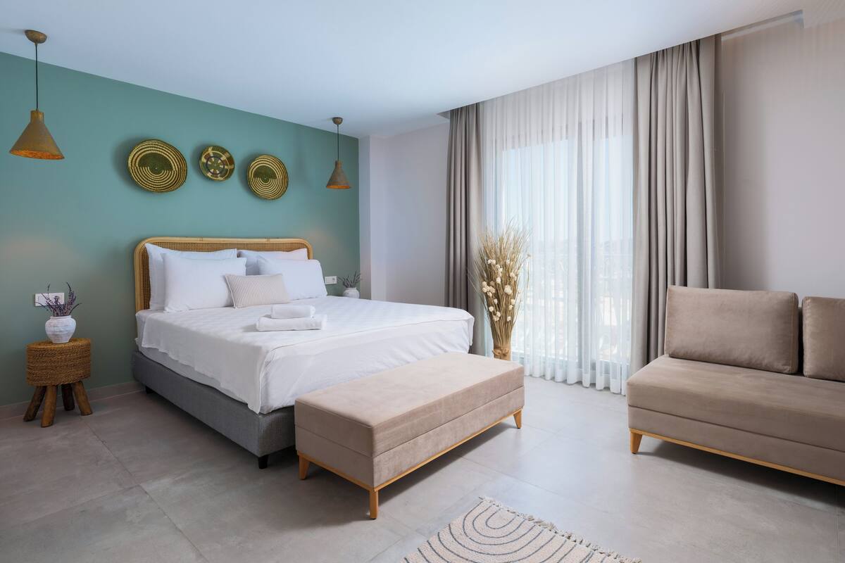 Een moderne slaapkamer met een bed, een bank en een klein tafeltje met een vaas.