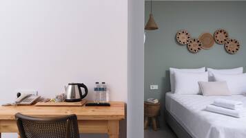 A room with a wooden desk, a chair, a bed with white bedding, and a wall with woven wall art.