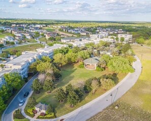 Residential area with detached houses and townhouses, surrounded by well-maintained lawns and mature trees.