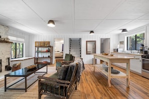 A spacious living area with a wooden floor, a fireplace, a dining table, and a kitchen area with modern appliances.