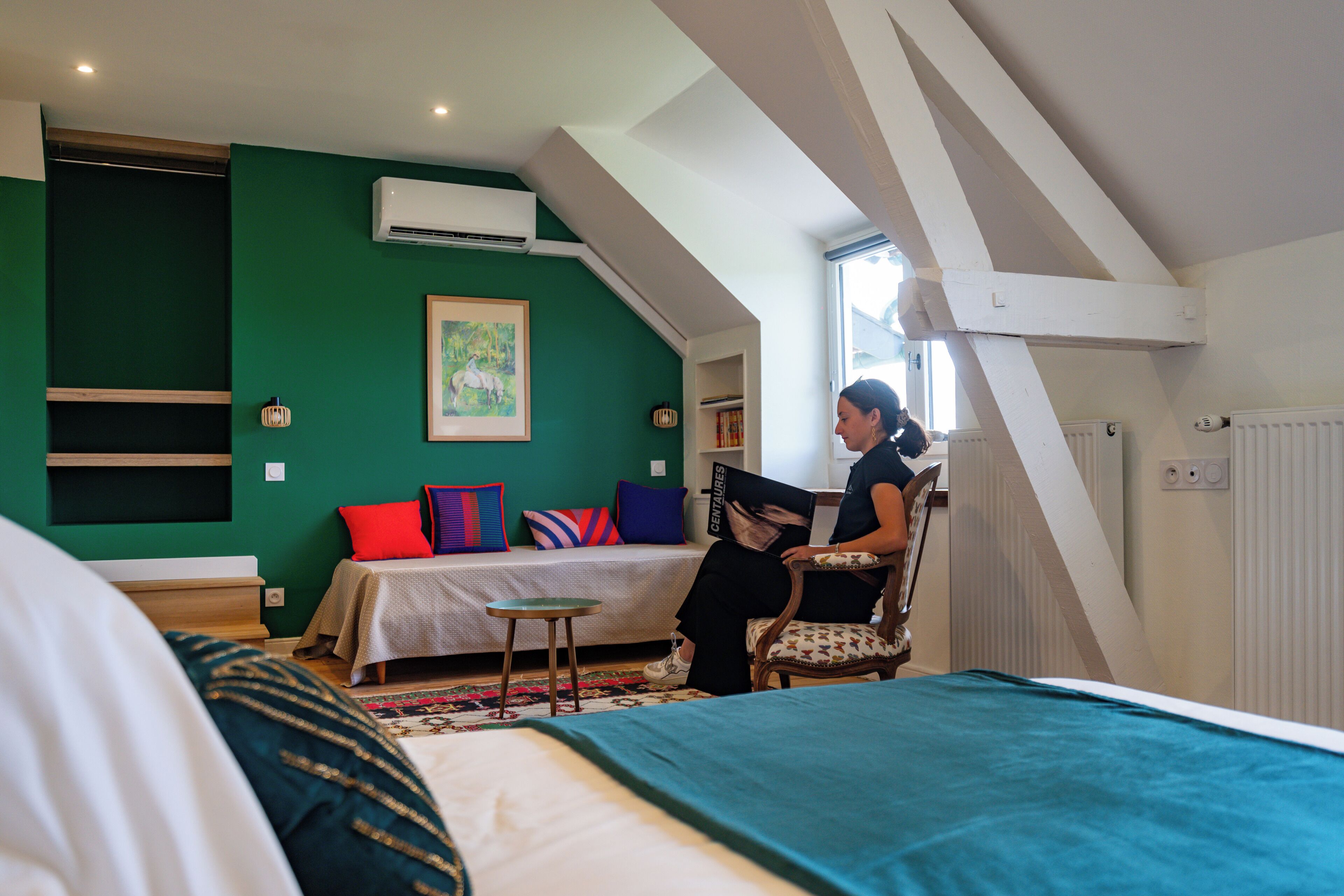 Une chambre à coucher comprenant un lit, une chaise, une petite table, une fenêtre et un appareil de climatisation.