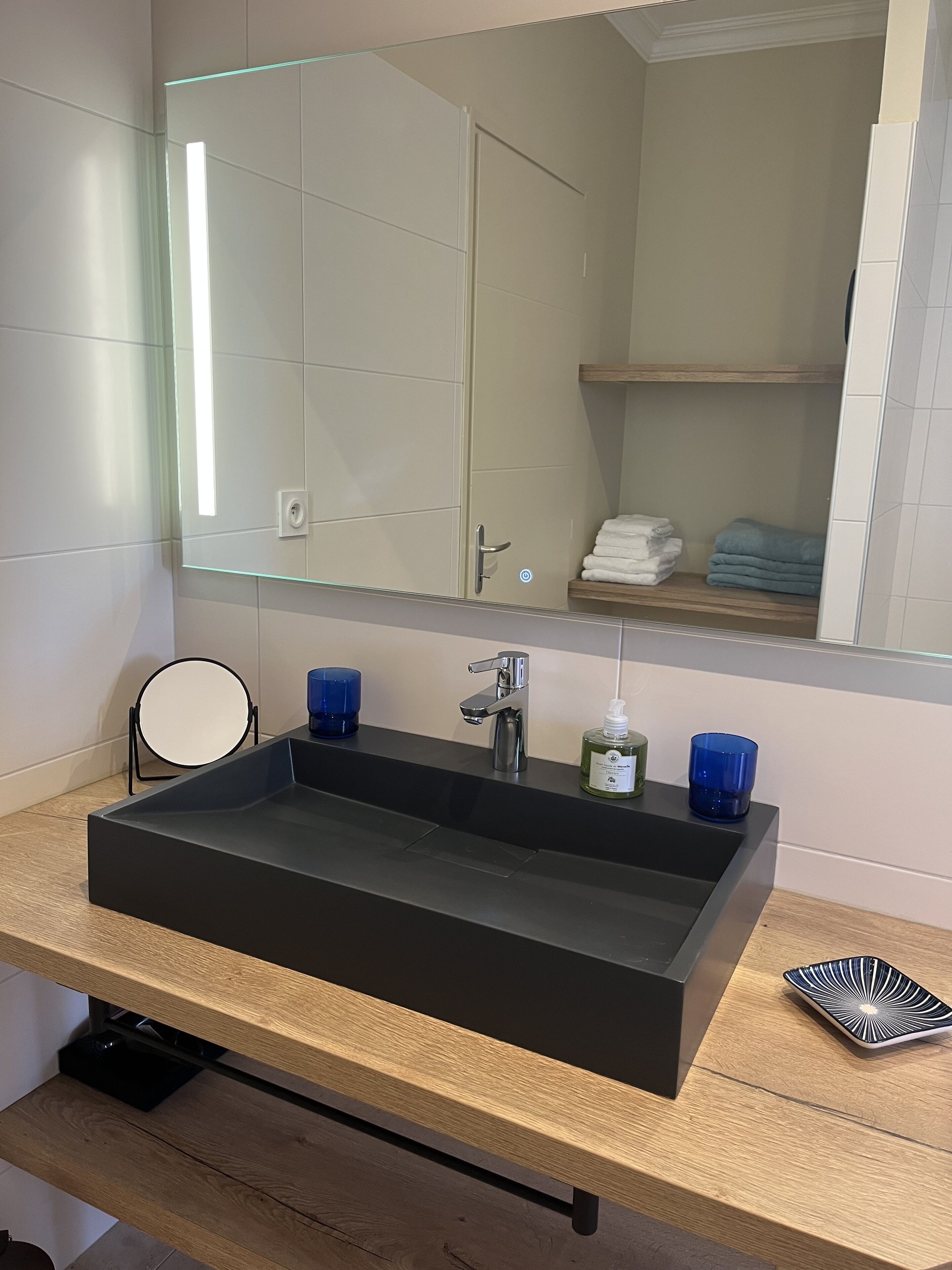 Un baño moderno con un lavabo rectangular, un espejo y un mueble de tocador de madera.